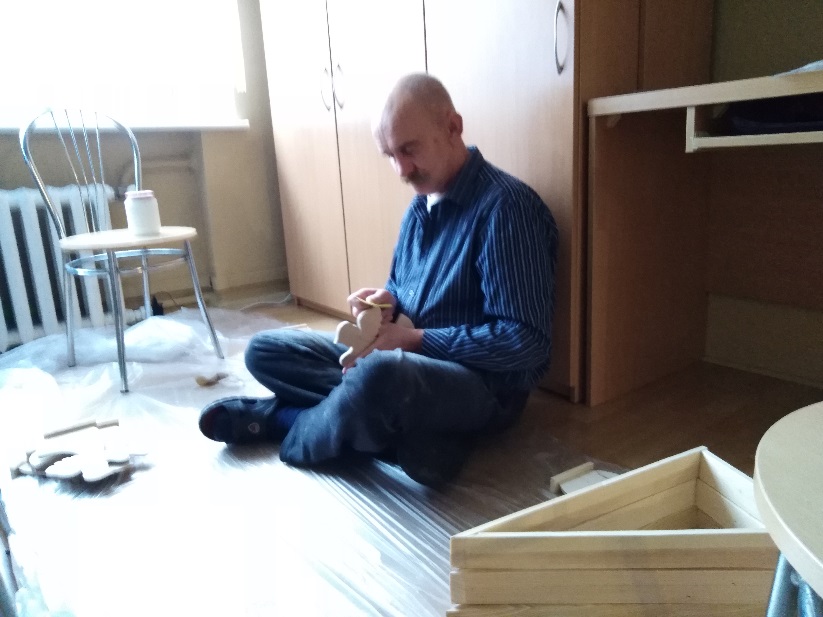 Mężczyzna szlifujący elementy drewniane.