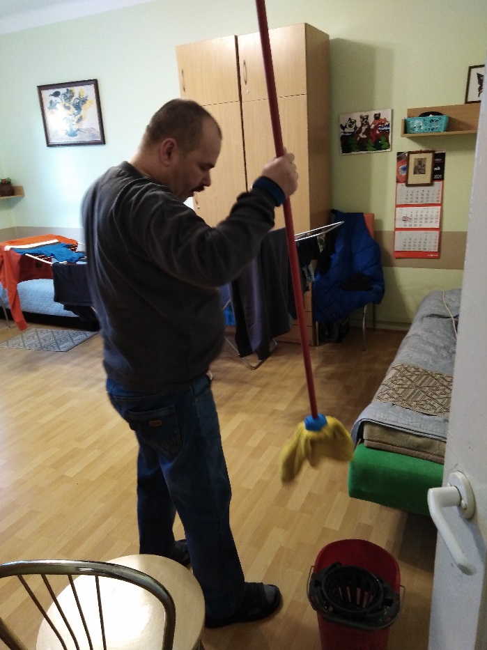 Mężczyzna trzymający mopa w ręce.
