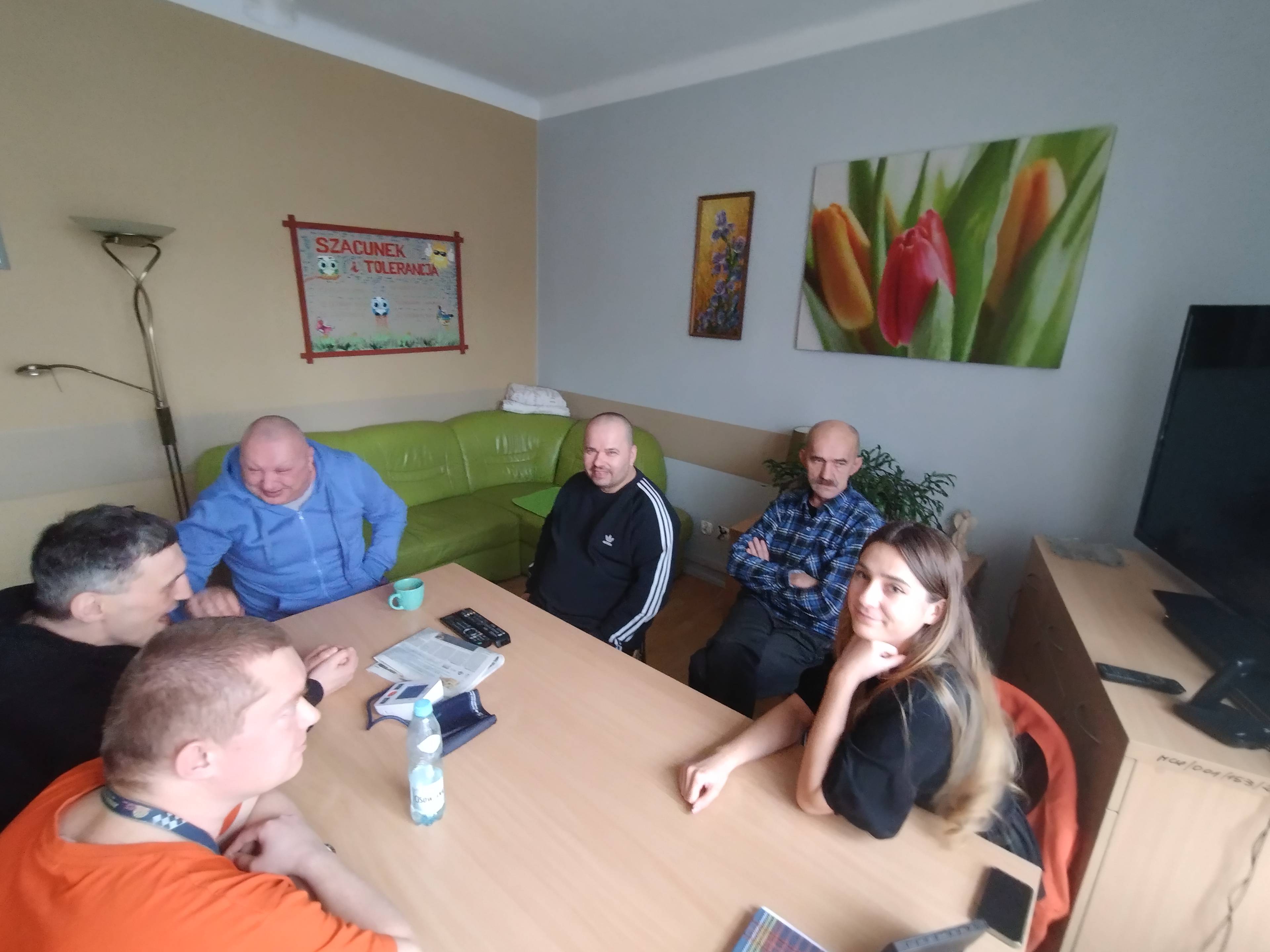 Pięciu mężczyzn i jedna kobieta siedzą przy stole rozmawiając.