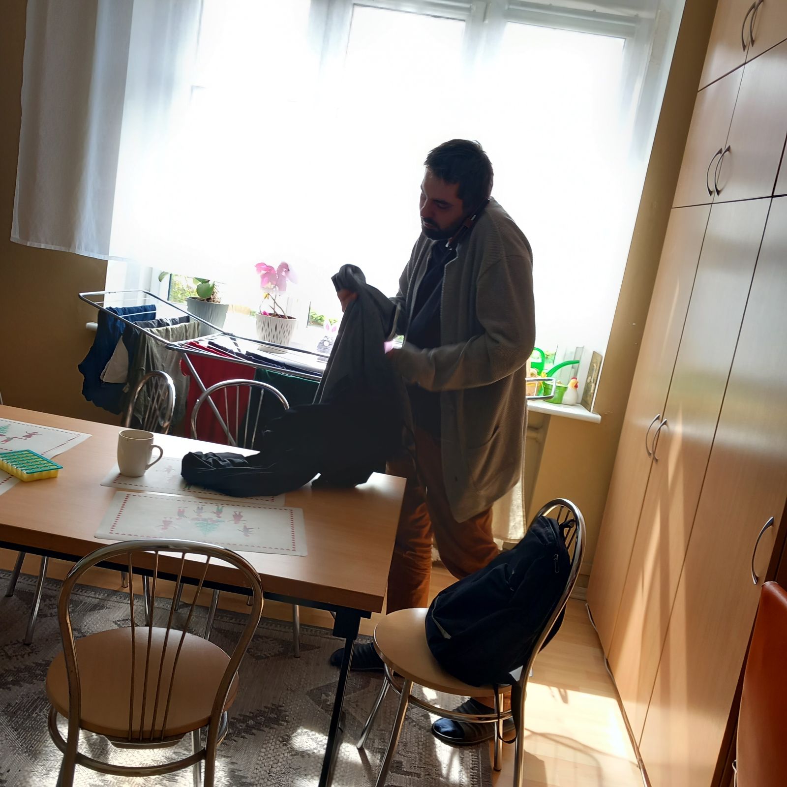 Mężczyzna składa odzież i rozmawia przez telefon.