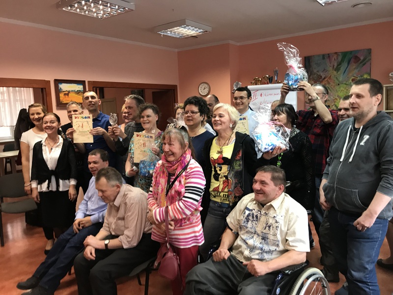 Grupa uśmiechniętych kobiet i mężczyzn pozujących do wspólnego zdjęcia z nagrodami i dyplomami w ręku 