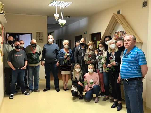 Dziewięciu mężczyzn oraz siedem kobiet trzymających kwiaty podarowane z okazji Dnia Matki.