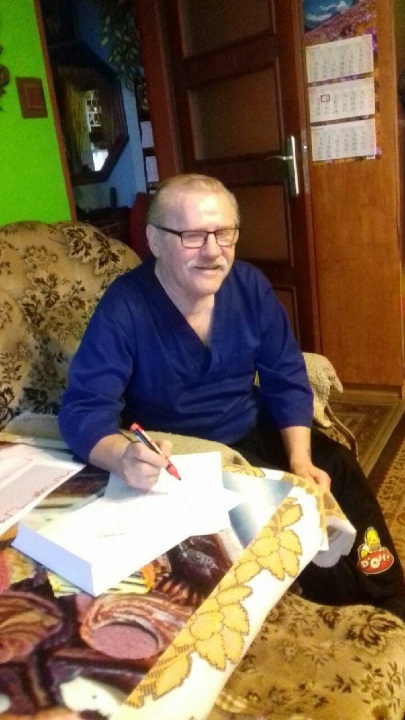 Mężczyzna siedzi w fotelu przy  ławie i rozwiązuje karty pracy. 