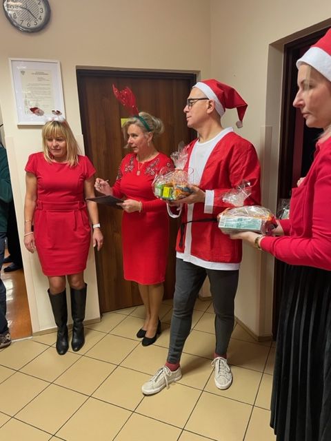 Grupa kobiet i mężczyzna  trzymają w dłoniach paczki świąteczne ze słodyczami.  