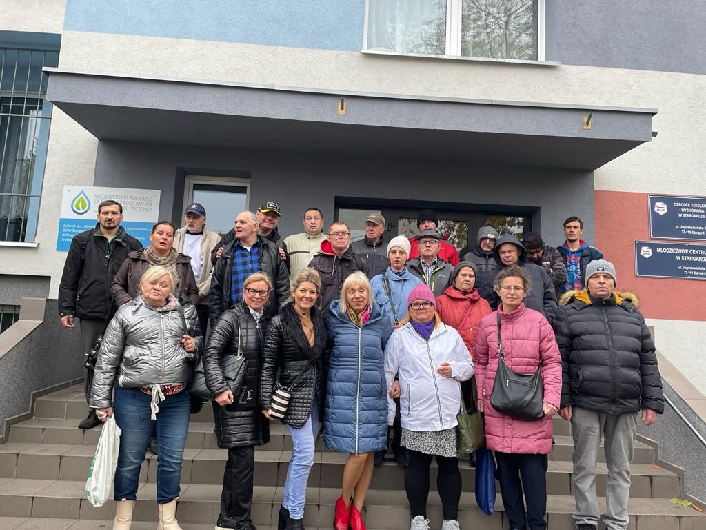 Grupa mężczyzn i kobiet stoi na schodach przed wejściem do  Ośrodka Szkolenia i Wychowania w Stargardzie. 