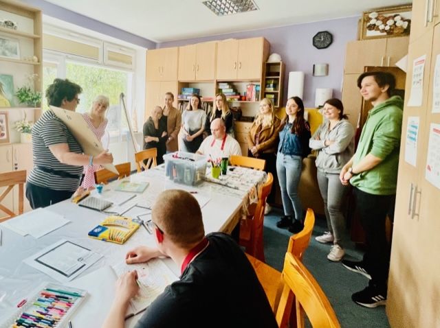 Grupa kobiet i mężczyzn ogląda obrazy.