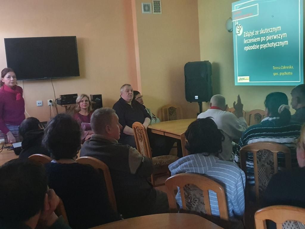 Grupa kobiet i mężczyzn słucha wykładu Pani Doktor na temat uzależnień i leczenia po pierwszym epizodzie psychotycznym.