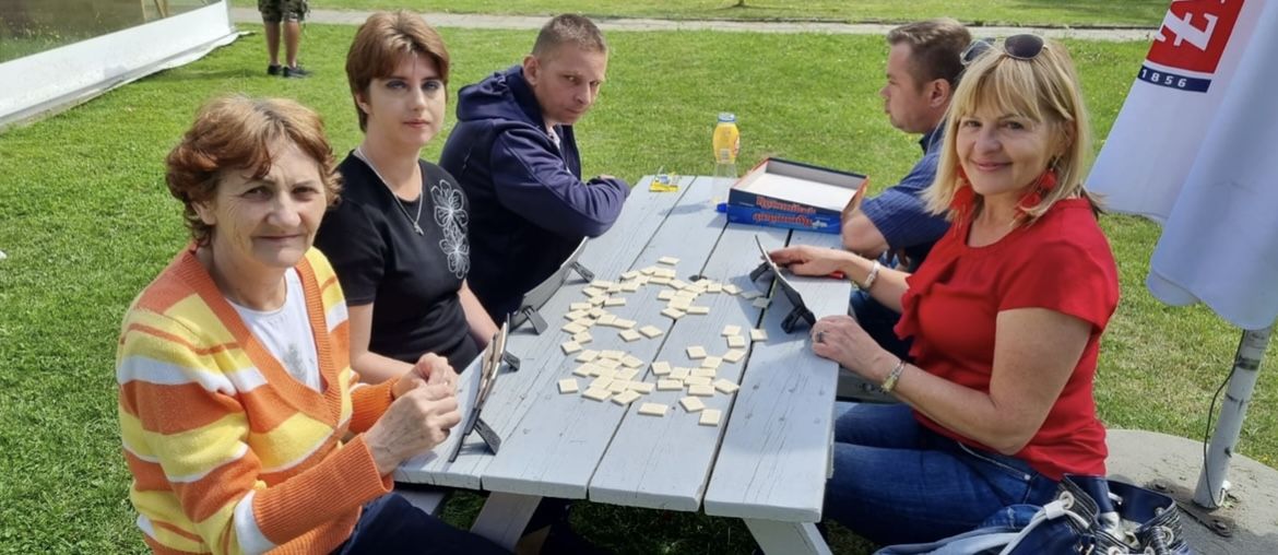 Grupka kobiet i mężczyzn gra w grę stolikową.  