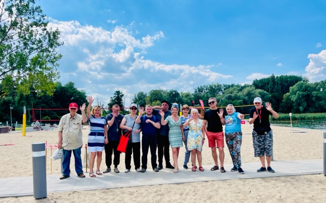 Grupa kobiet i mężczyzn stoi plaży nad Jeziorem Dąbskim pozując do zdjęcia. 