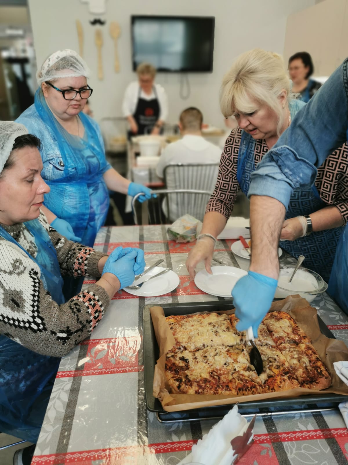 Kobiety i mężczyźni przygotowują pizzę.  
