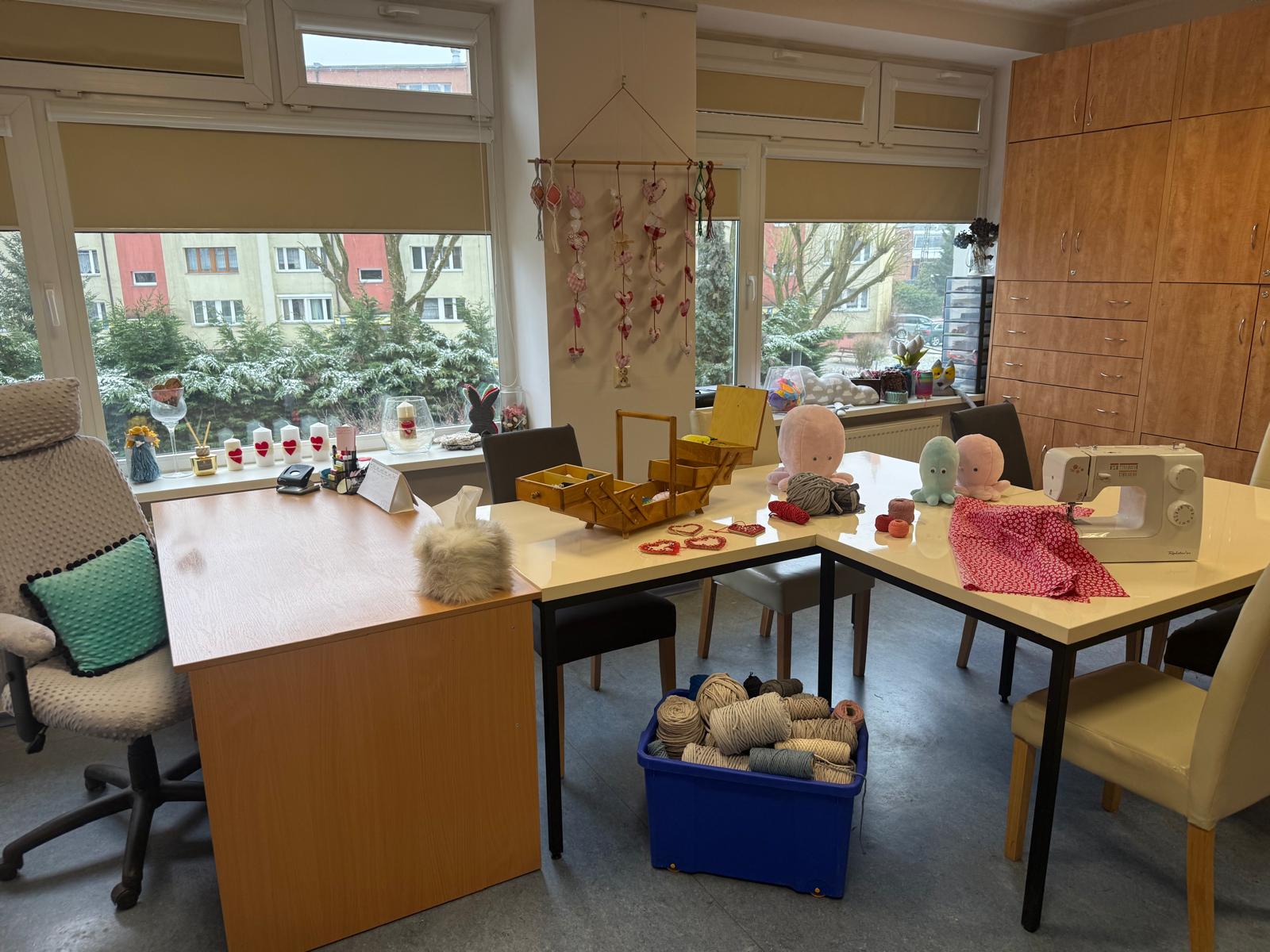 Pomieszczenie z oknem,stół z krzesłami i ozdobami ze sznurka bawełnianego.