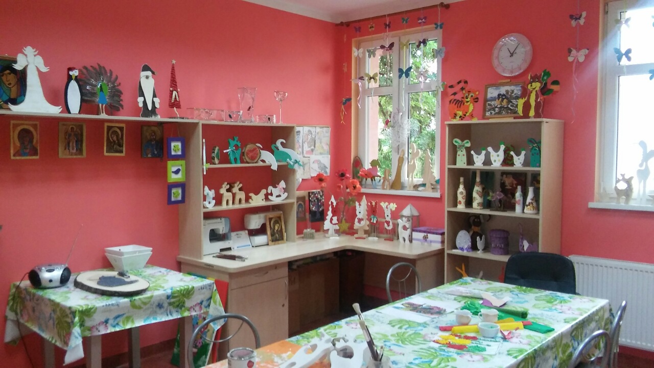 Pracownia plastyczna z dwoma stołami oraz krzesłami. Dekoracje z drewna