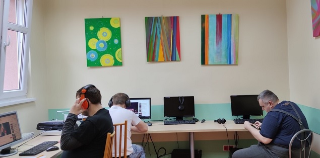 Trzech mężczyzn siedzi przy komputerach.