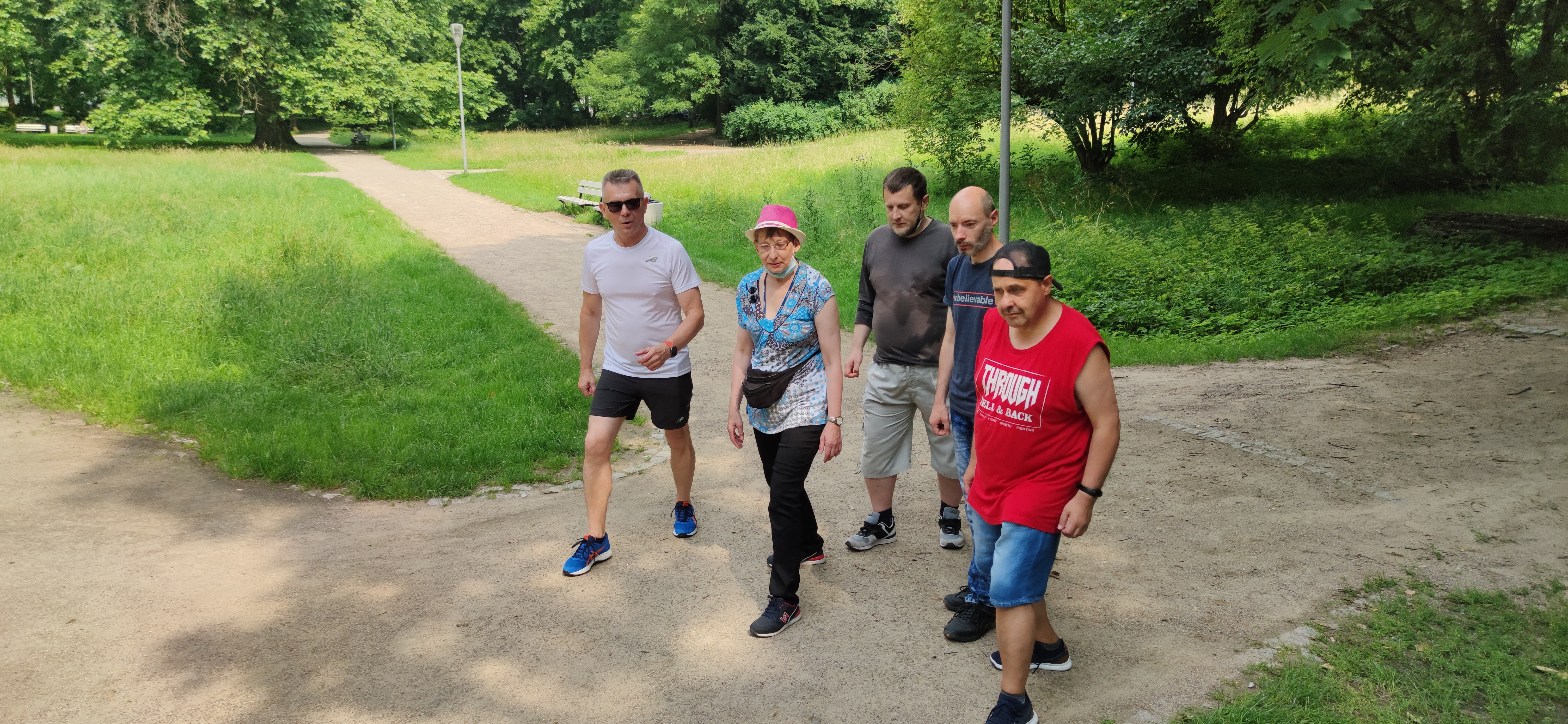 Grupa biegaczy na aleii w parku ,przed startem.