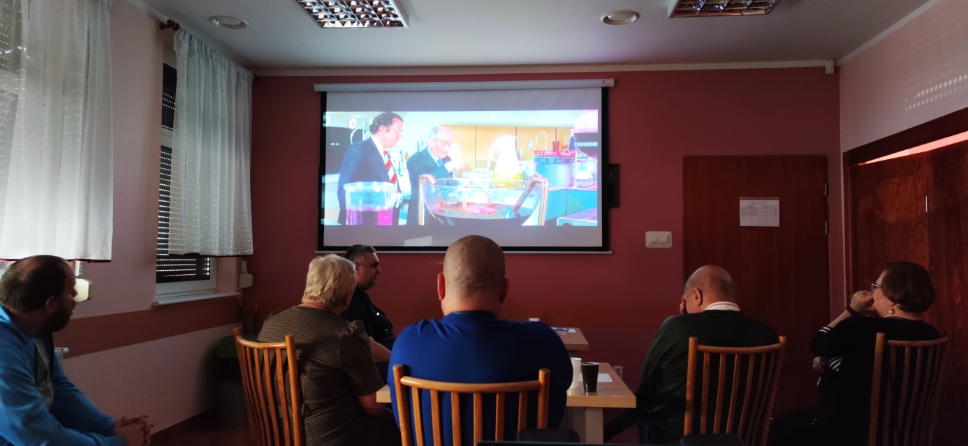 Grupa osób patrzy na film wyświetlany na ekranie.