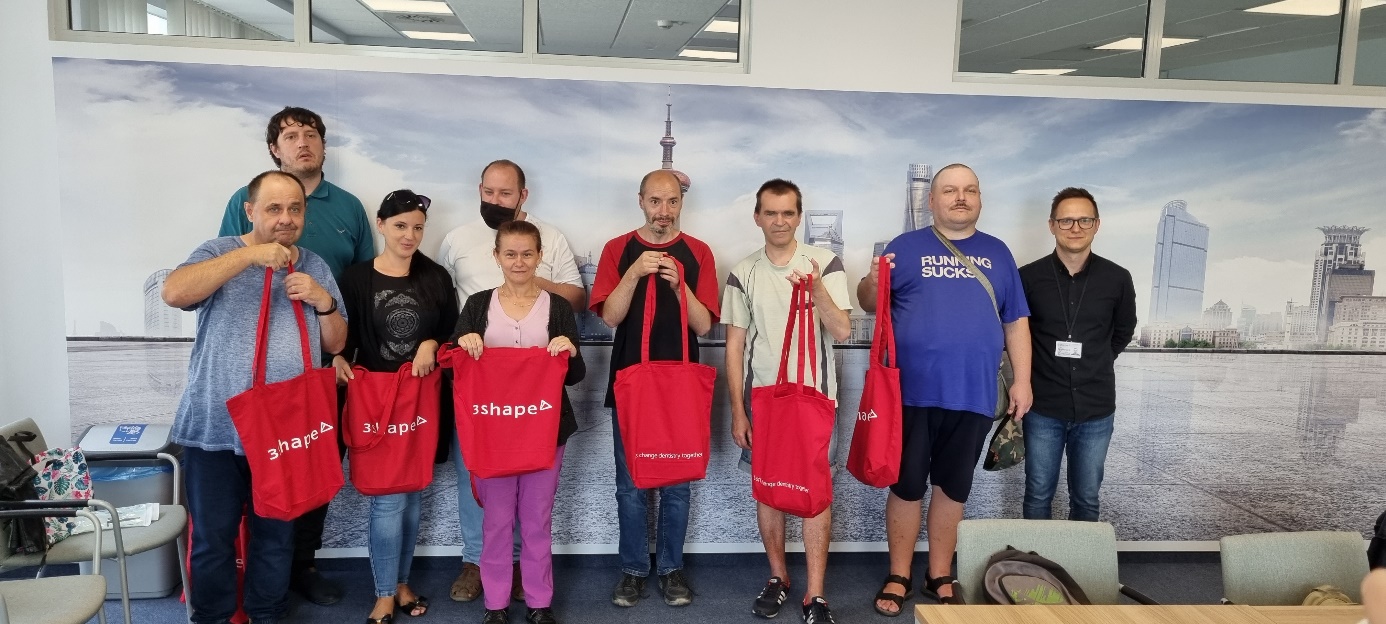Grupa osób pod ścianą z reklamą.