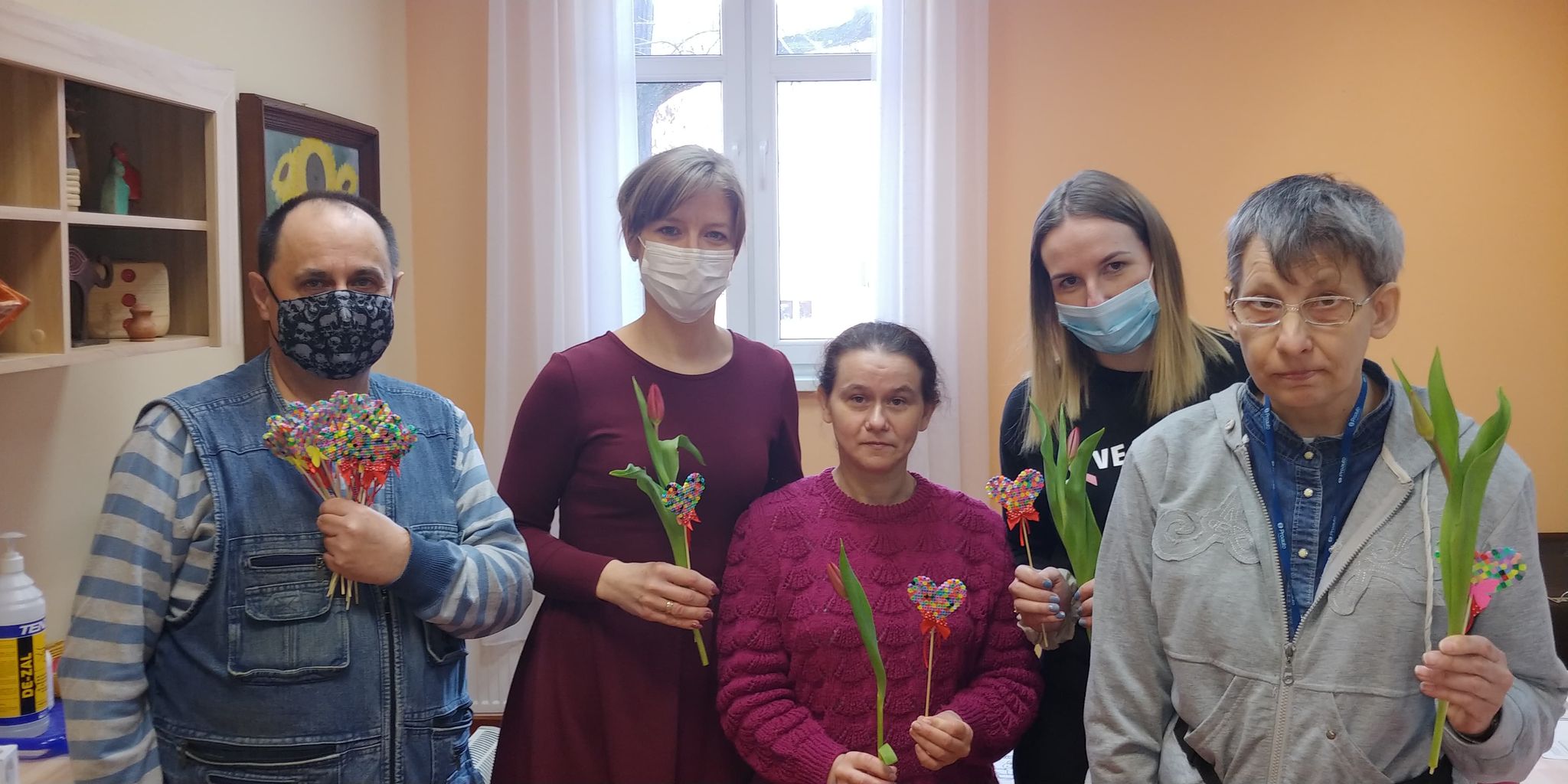 Cztery kobiety i mężczyzna z kwiatami.