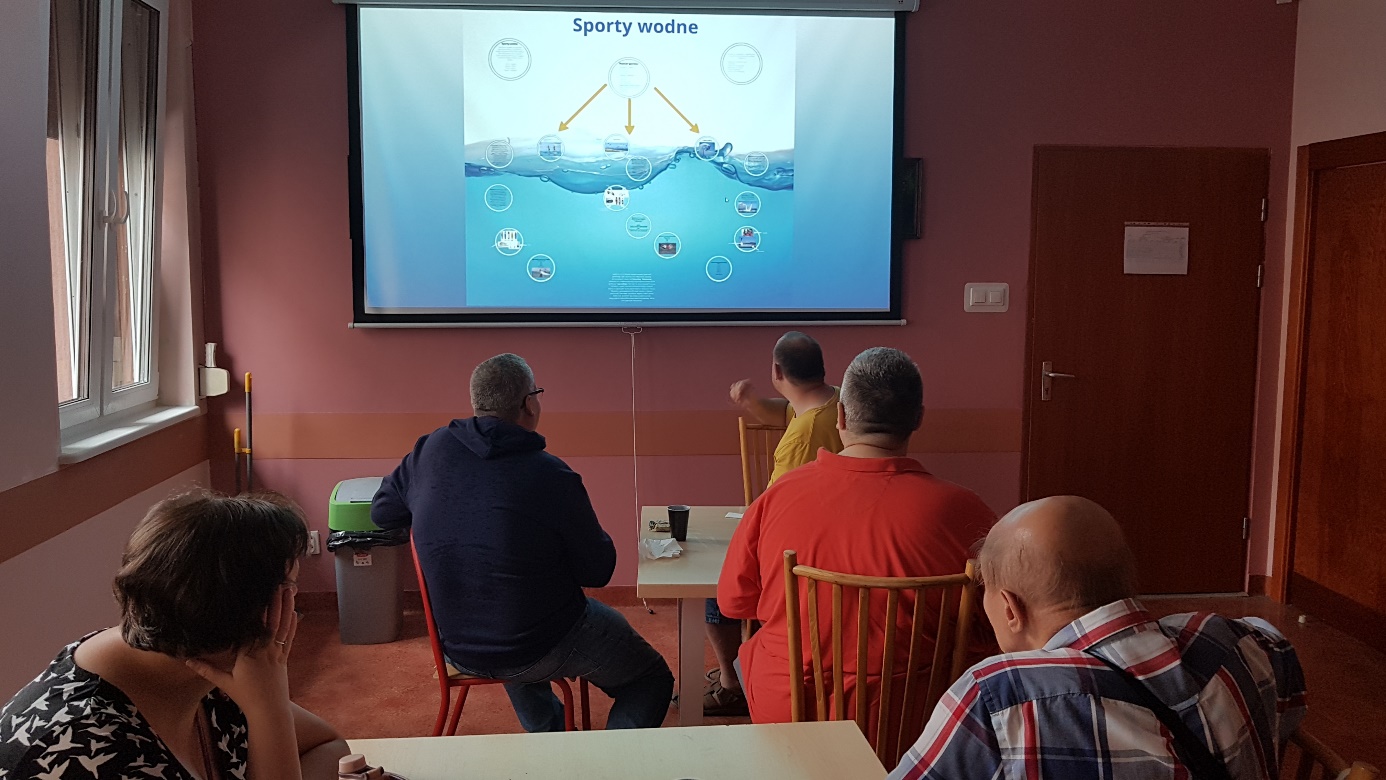 Grupa ludzi patrzy na ekran na którym wyświetla się prezentacja.