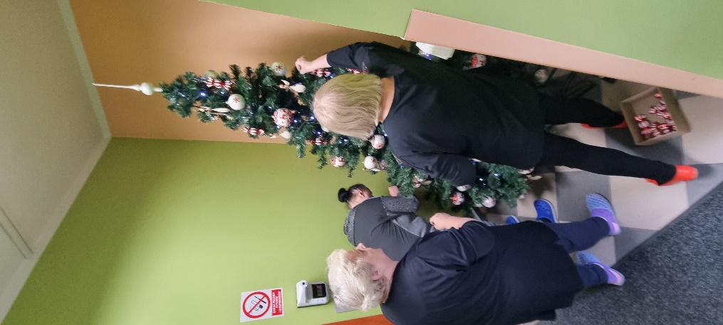 Trzy osoby ubieraja choinkę.