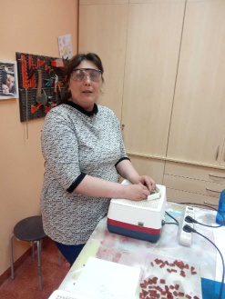 Kobieta stojąca przy stole na którym stoi szlifierka do szkła.