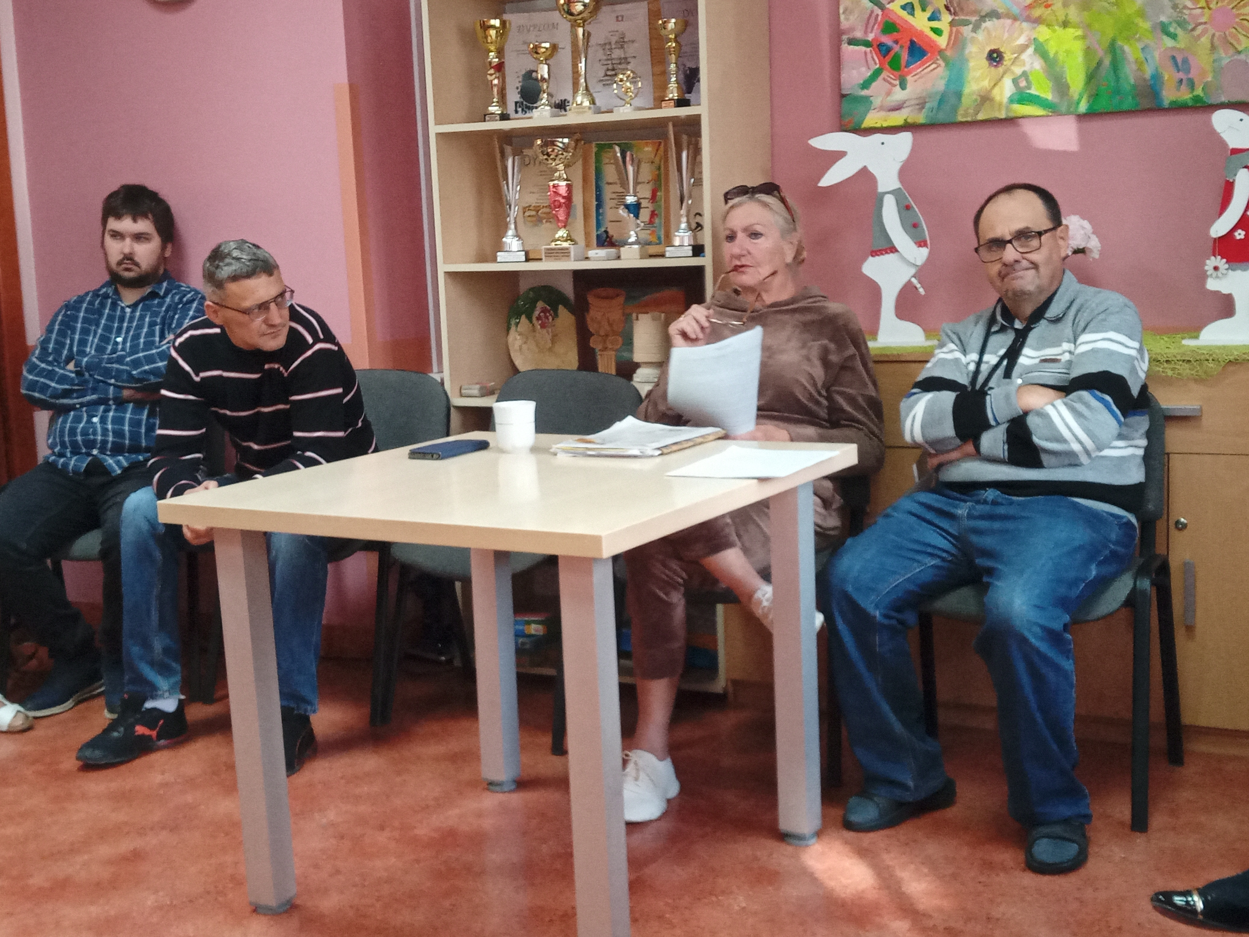 Pani Jadwiga siedzi z uczestnikami przy stole.