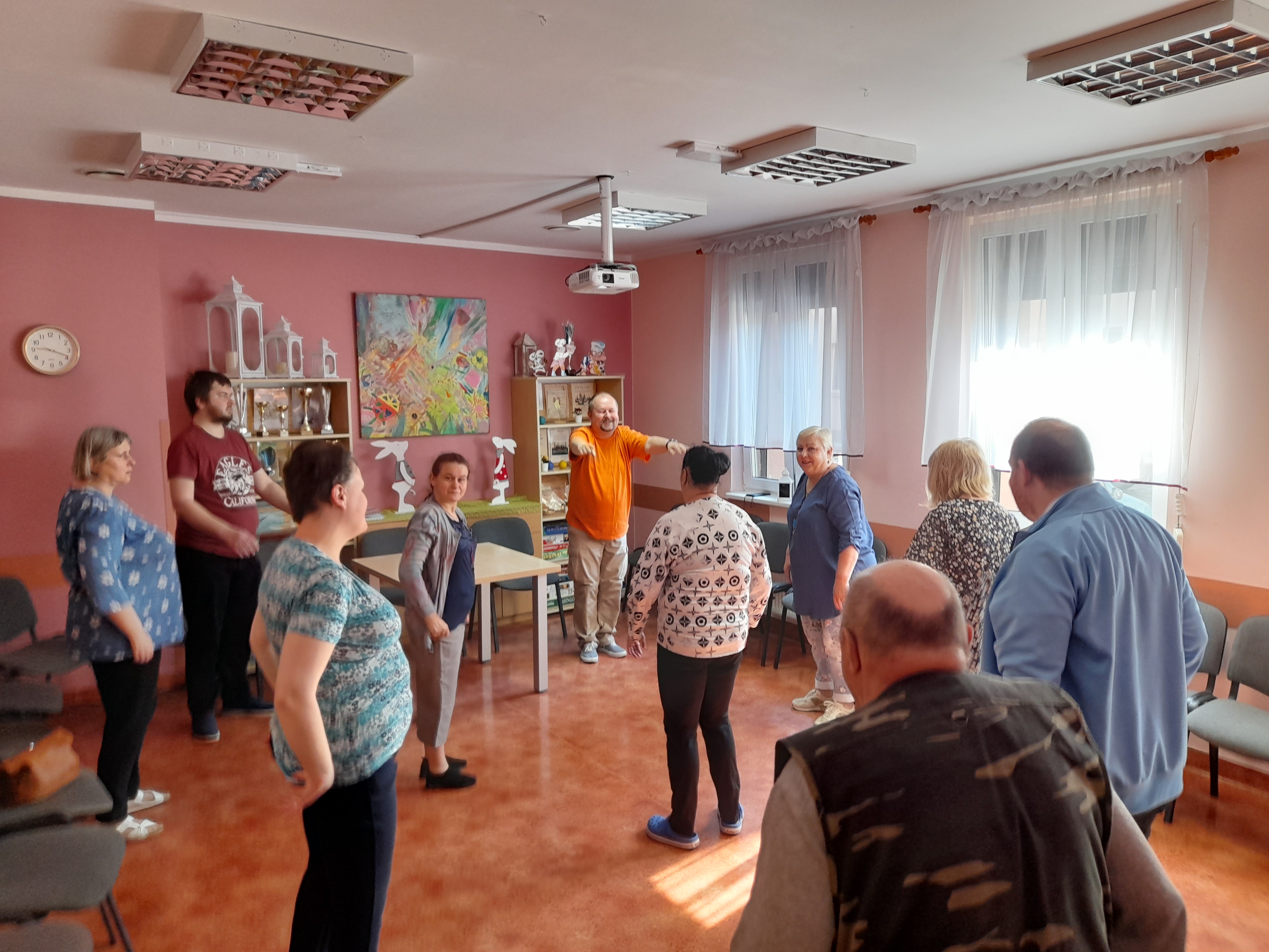 Grupa osób podczas ćwiczeń na sali.