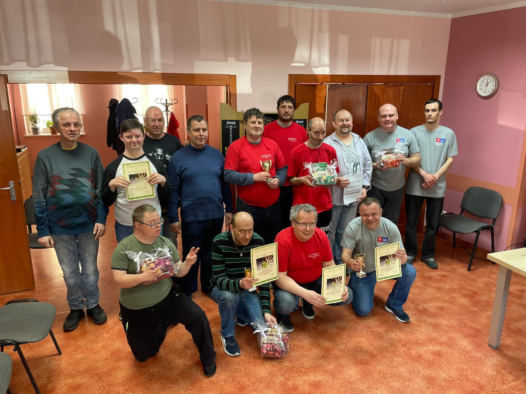 Grupa osób  trzymająca w dłonisch dyplomy i nagrody.