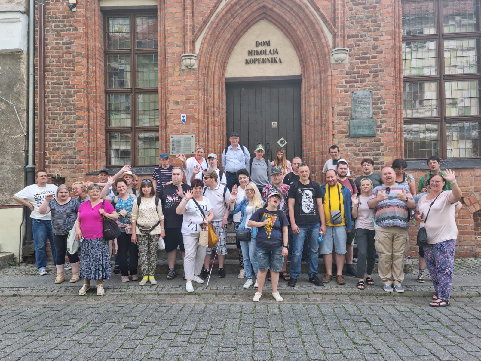 Duża grupa osób stoi pod domem Mikołaja Kopernika.