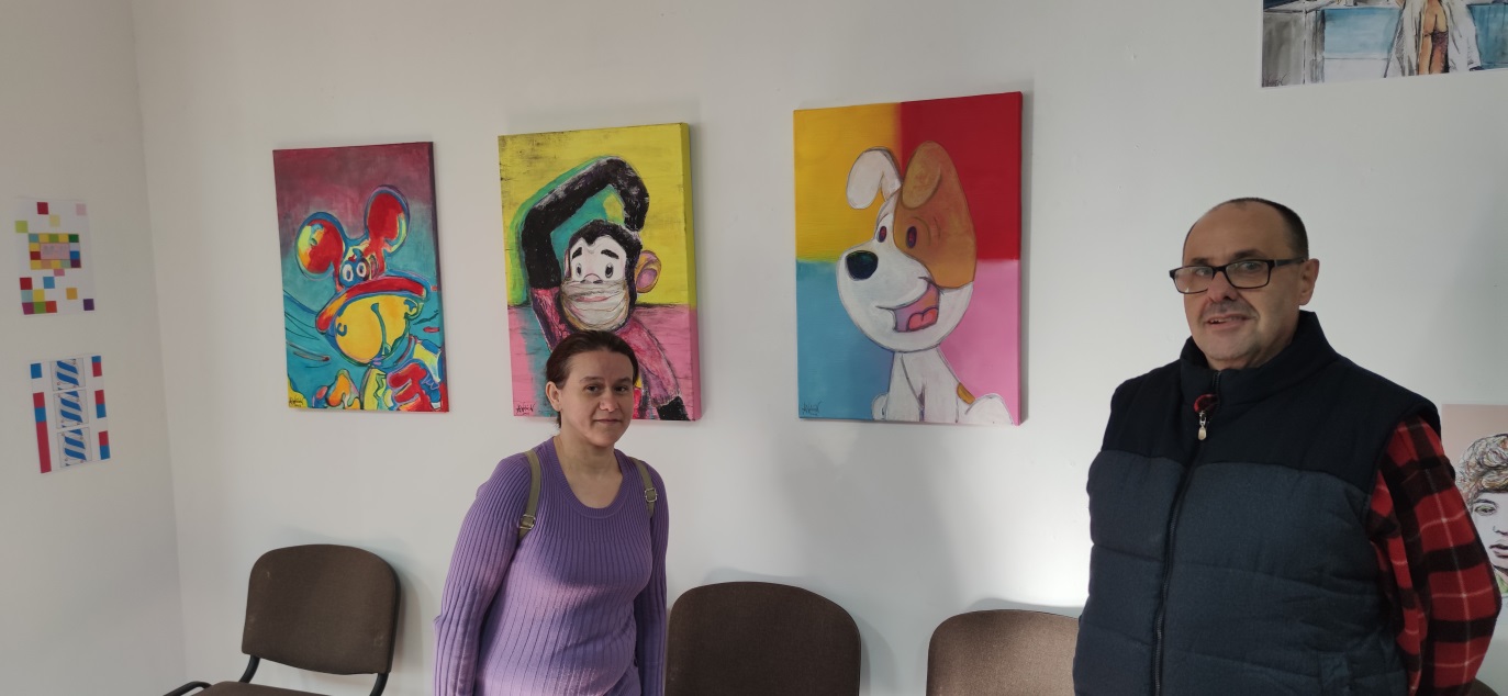 Dwie osoby stoją przed ścianą z obrazami