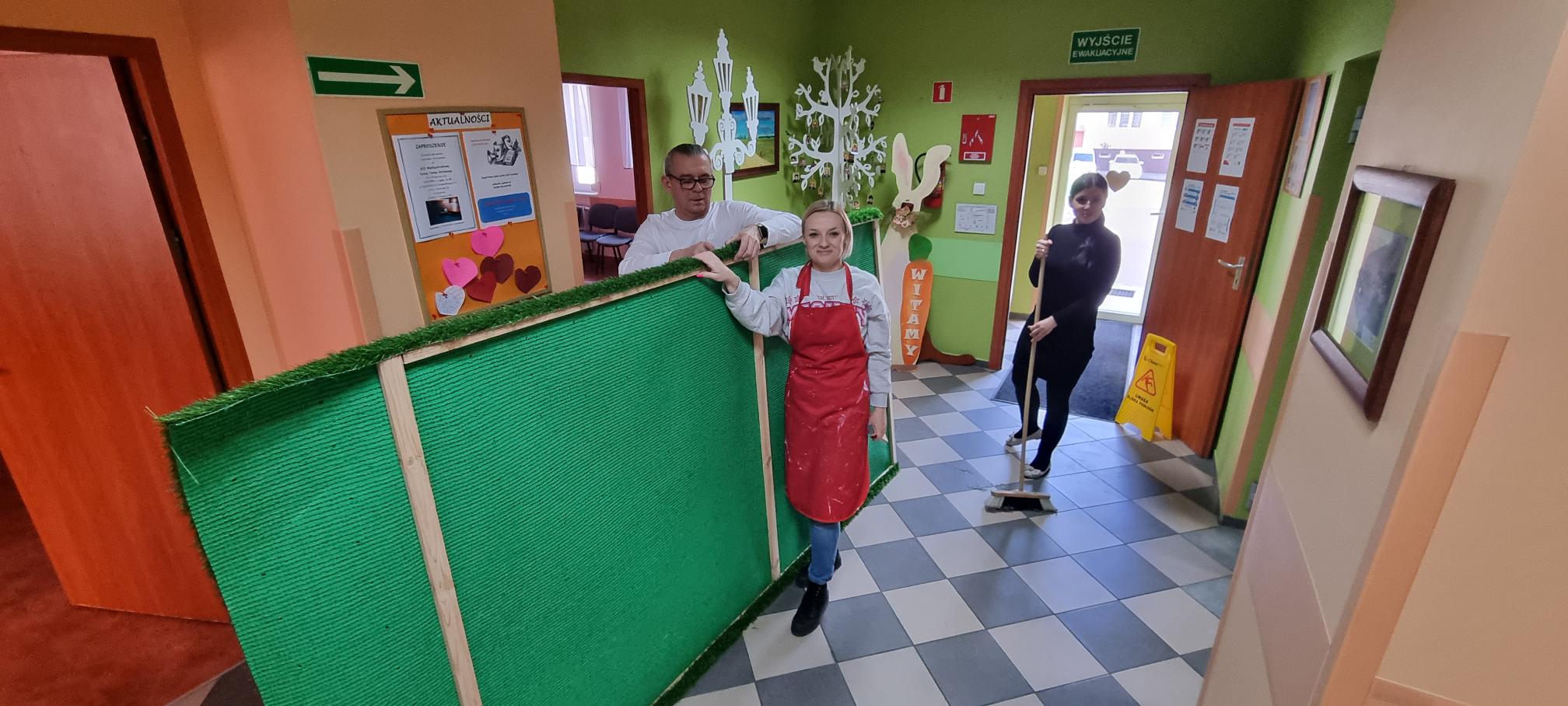 Trzy osoby montują wiosenną dekorację.