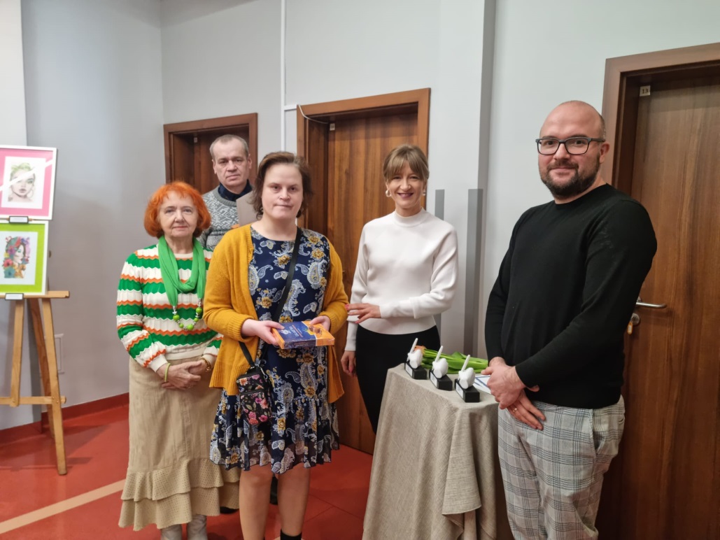 Osoby patrzą w obiektyw trzymając dyplomy.