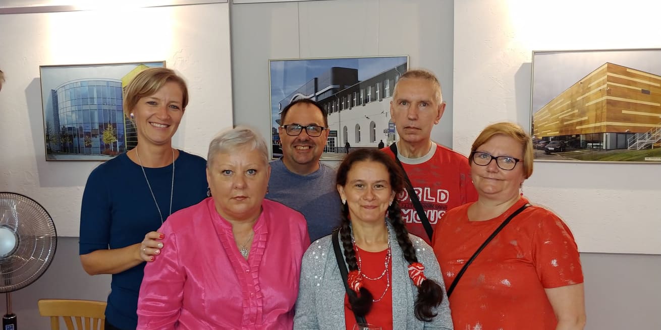 Ludzie stoją za nimi wiszą na ścianie duże zdjęcia Szczecina.