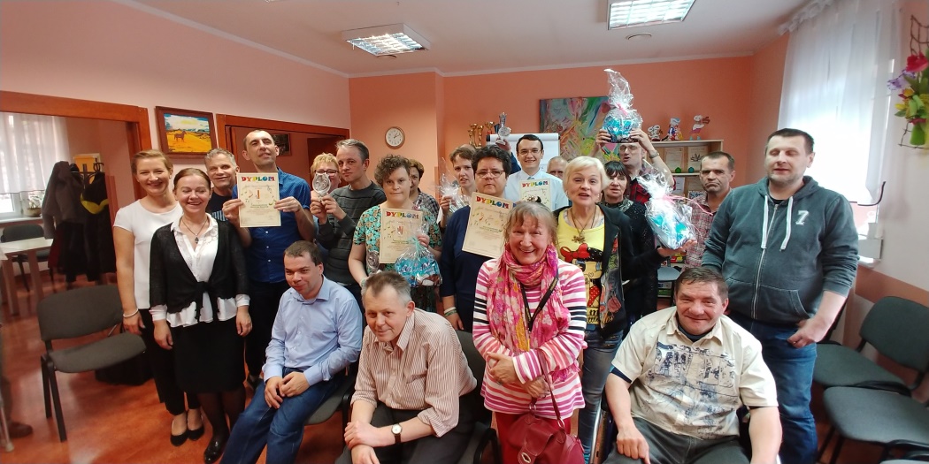 Grupa osób siedzi i stoi razem ,trzymają dyplomy.