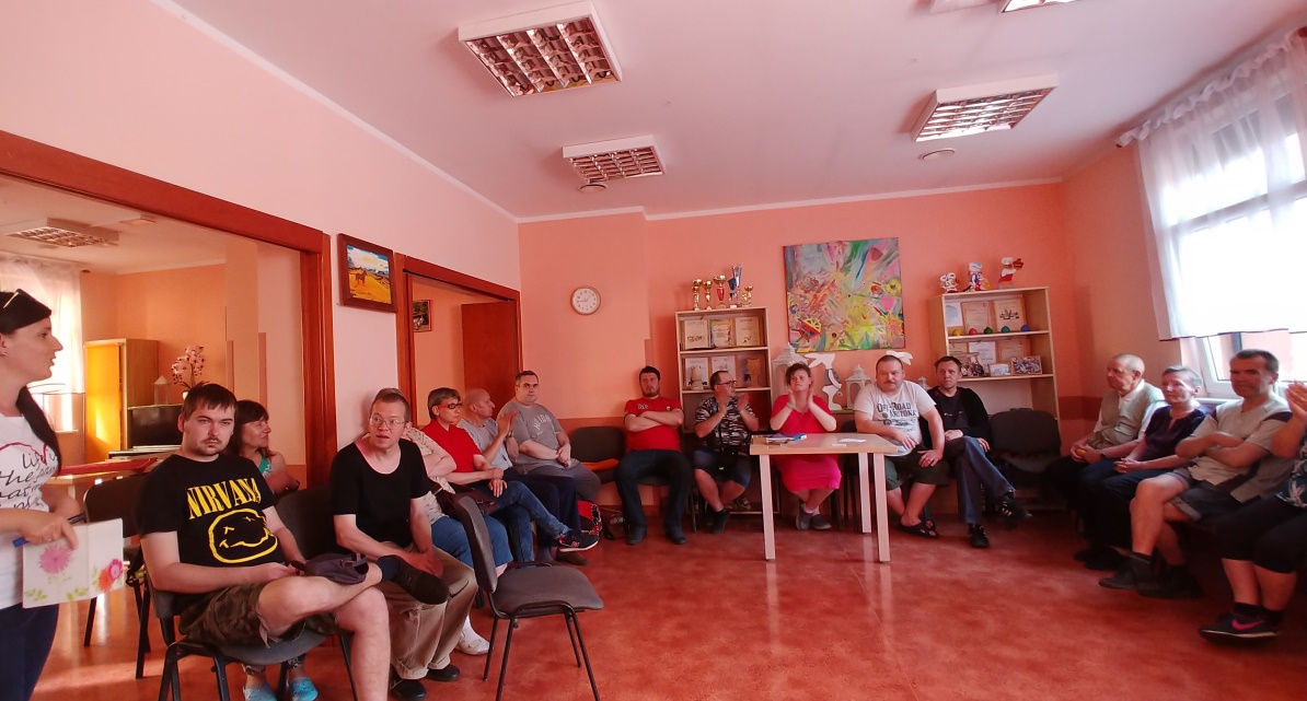 Kobieta stoi z boku ,ludzie siedzą do okoła.