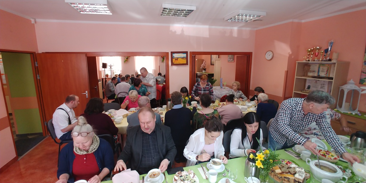 Kobiety i mężczyźni siedzą za stołami i jedzą posiłek świąteczny.