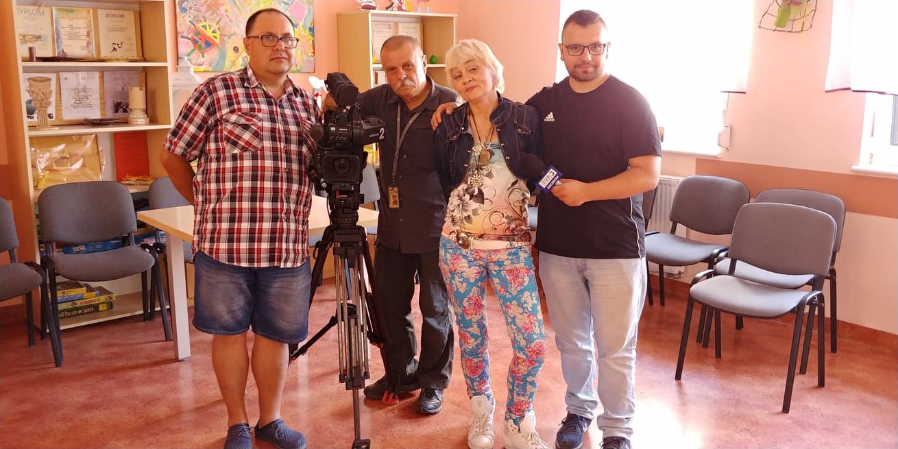 Kobieta i trzech mężczyzn stoi przy kamerze telewizyjnej.