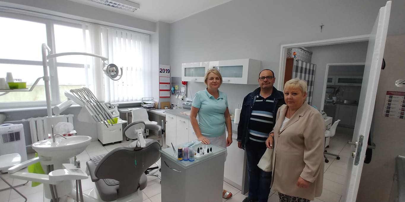 Dwie kobiety i mężczyzna soją za fotelem dentystycznym