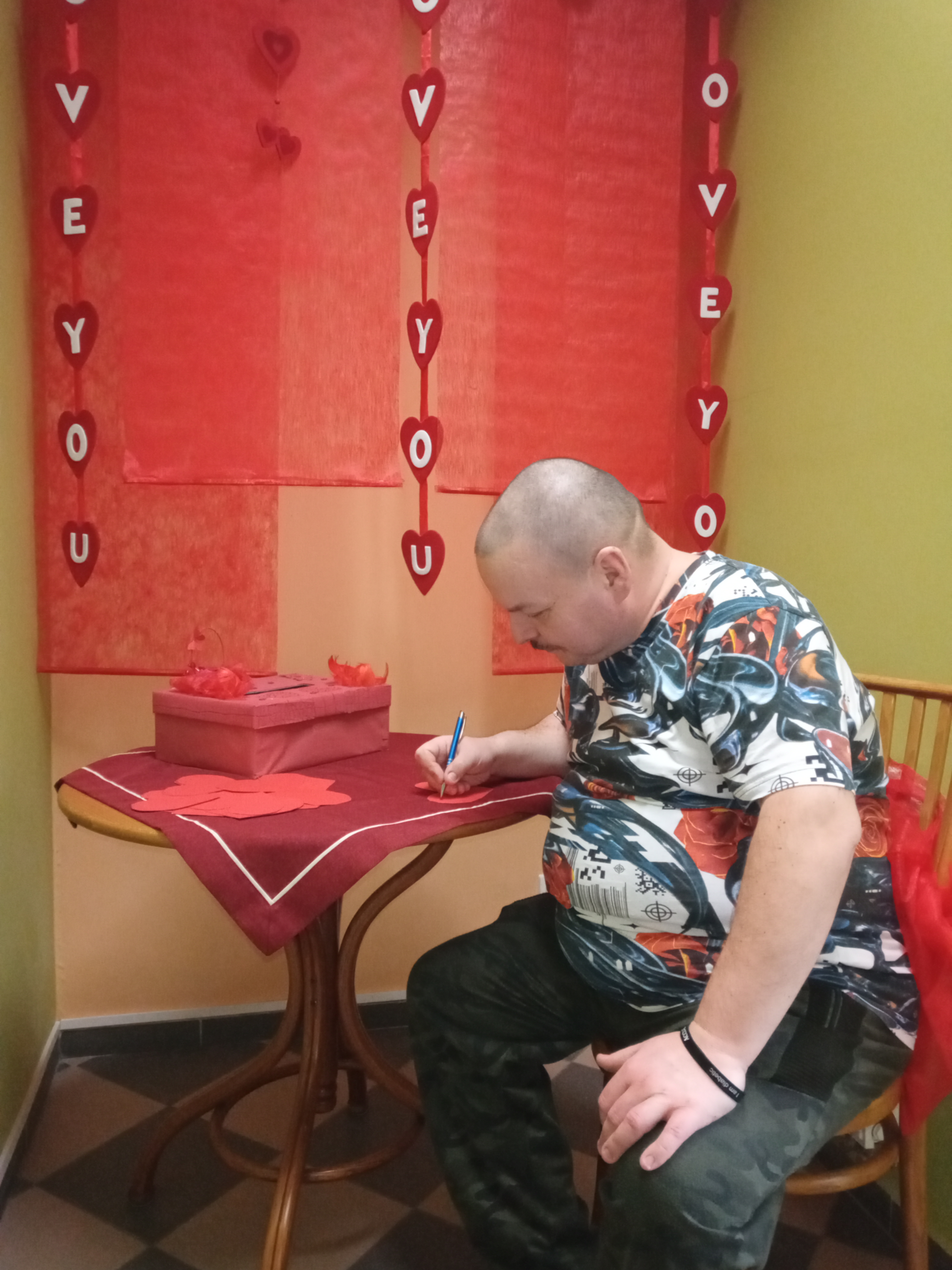 Mężczyzna siedzi przy stole i pisze kartkę.