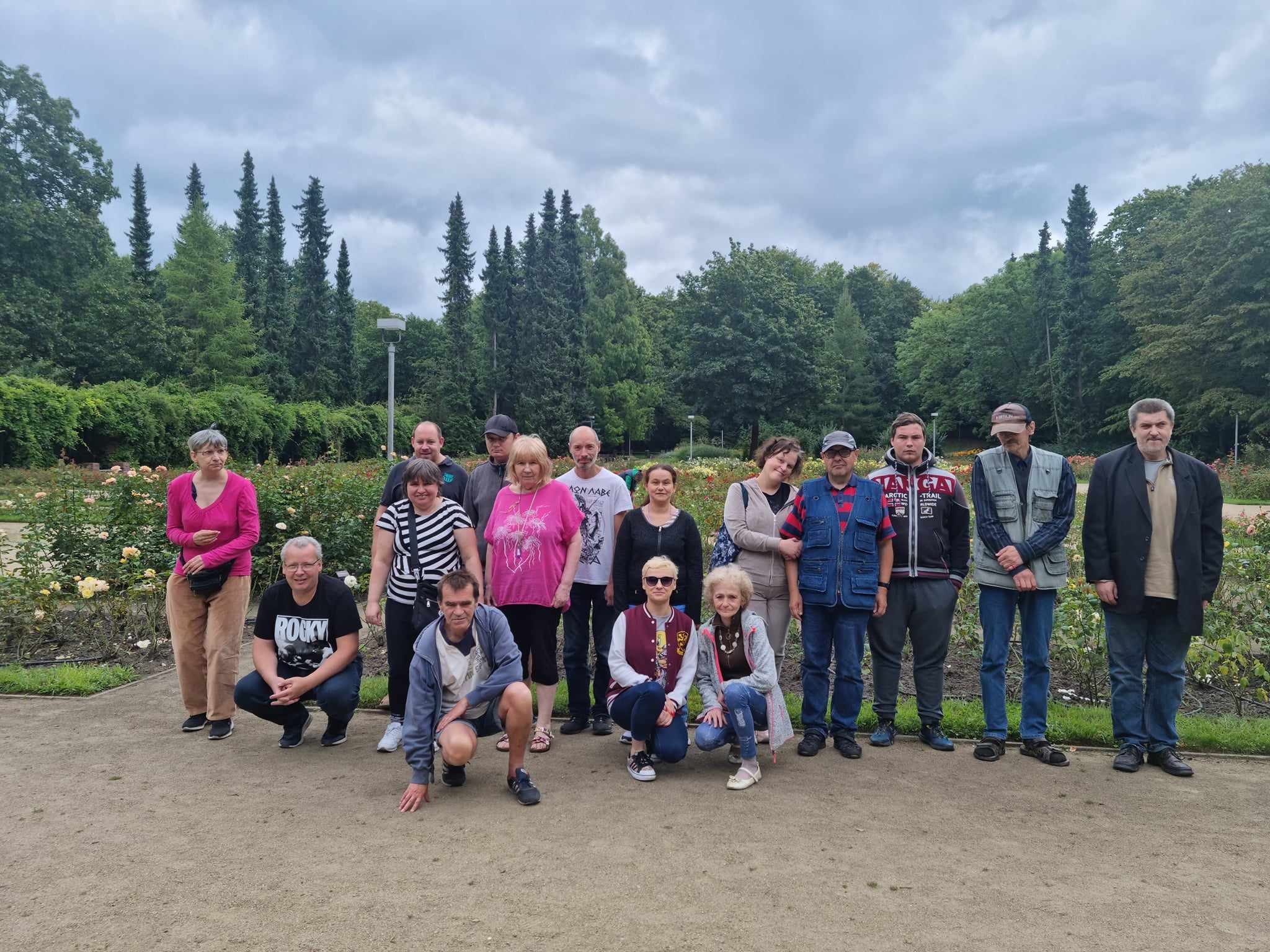 Grupa osób pozuje do zdjęcia na tle róż.