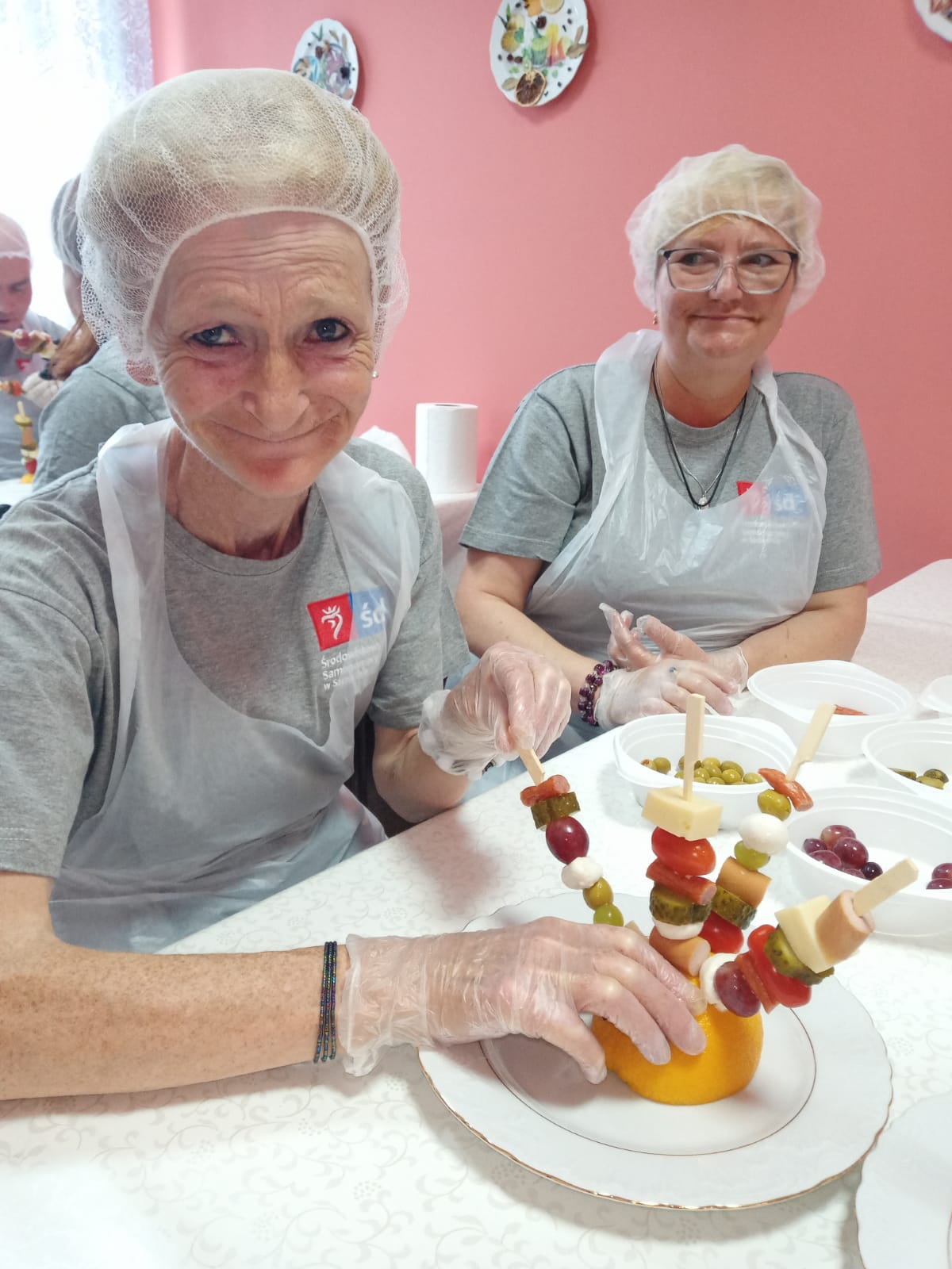 Kobiety siedza  przy stole w czepkach na włosach.