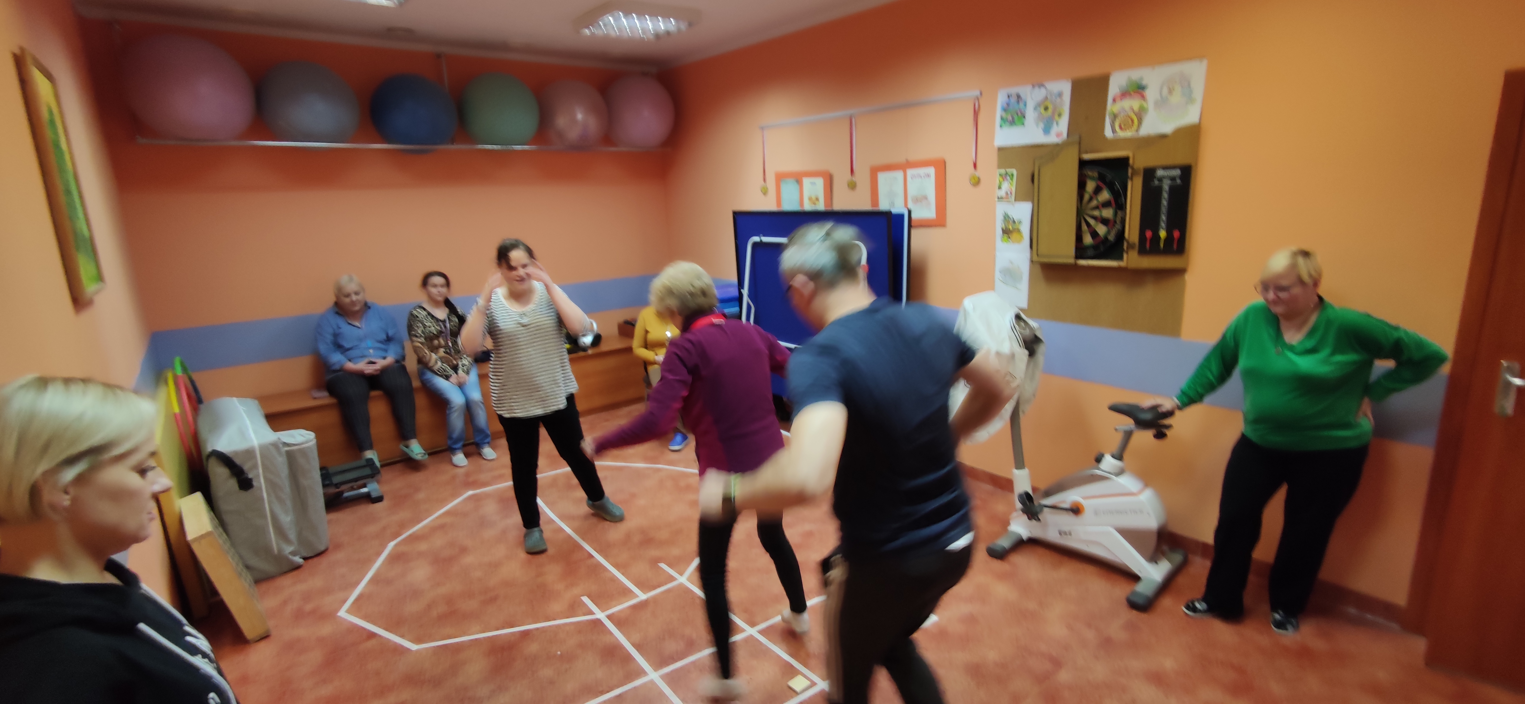 Ludzie skaczą nad naklejoną na ziemi figurą.