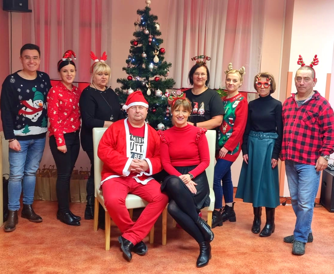 Grupa osób pozuje do zdjęcia w przebraniach świątecznych.