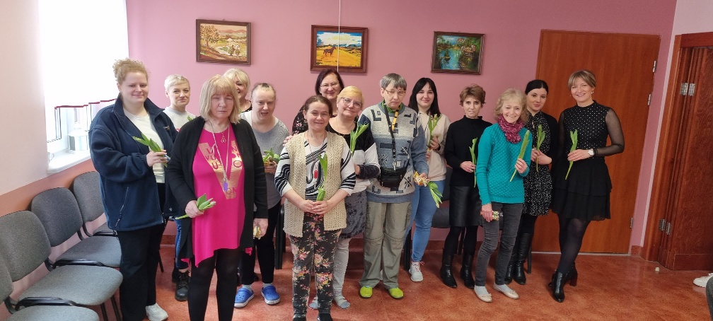 Grupa kobiet stoi z kwiatami z okazji święta kobiet.