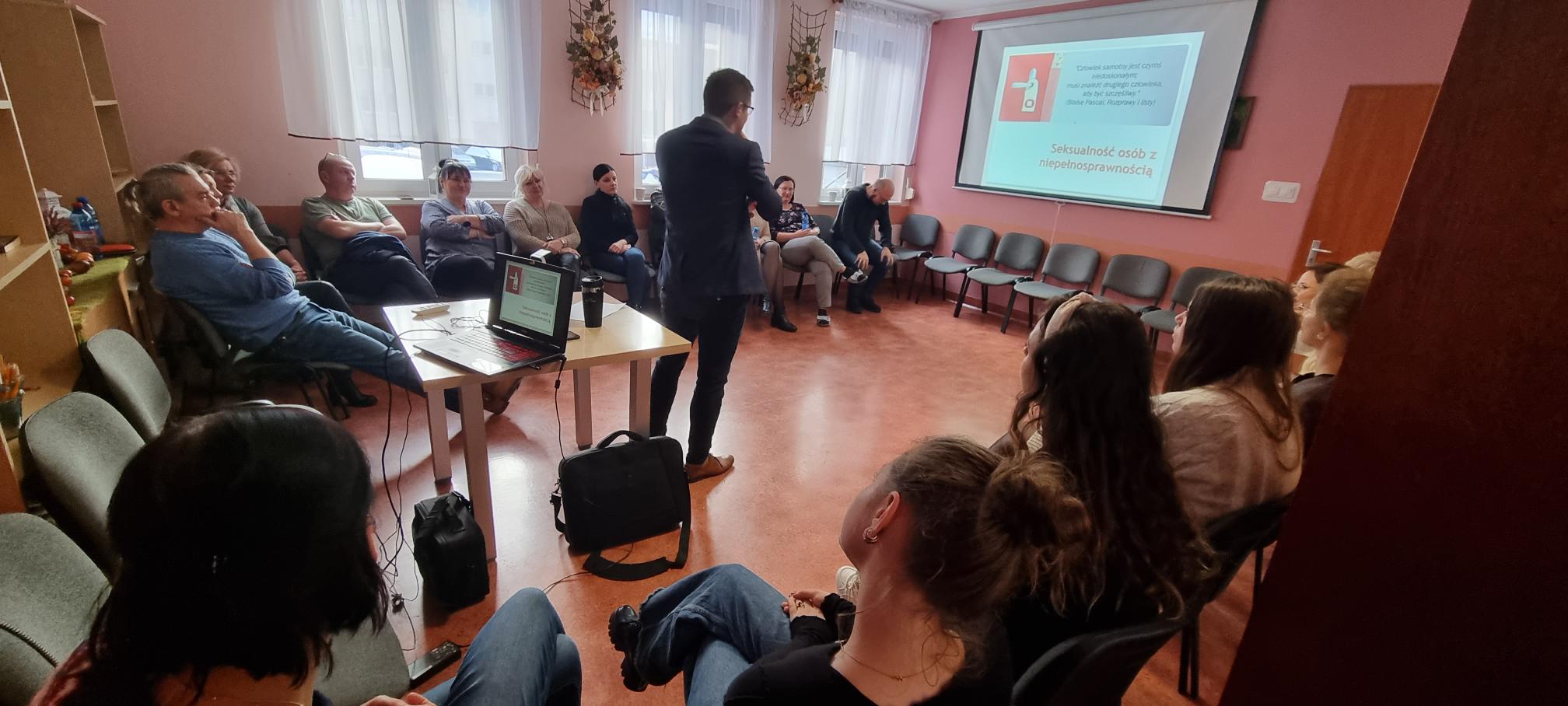 Prelegent porusza się pomiędzy słuchającymi go słuchaczami którzy siedzą w kręgu.