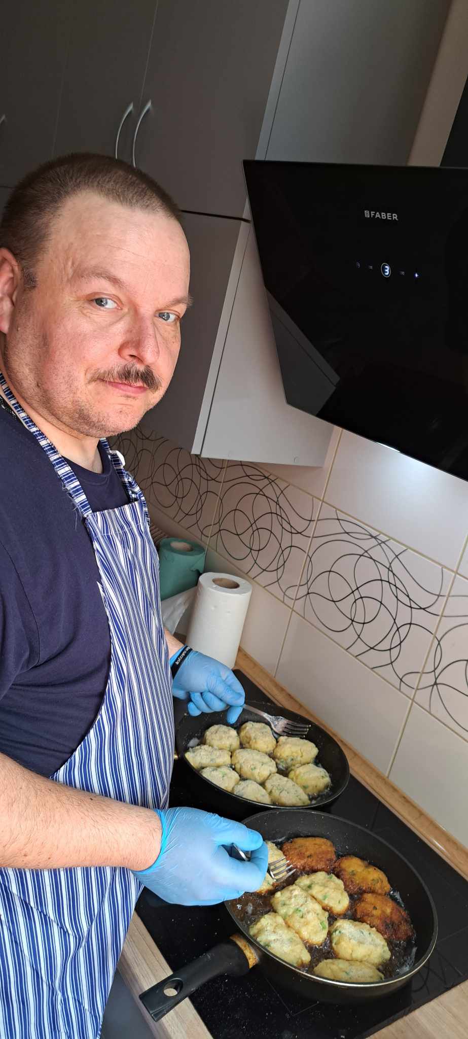 Mężczyzna stoi nad patelnią.