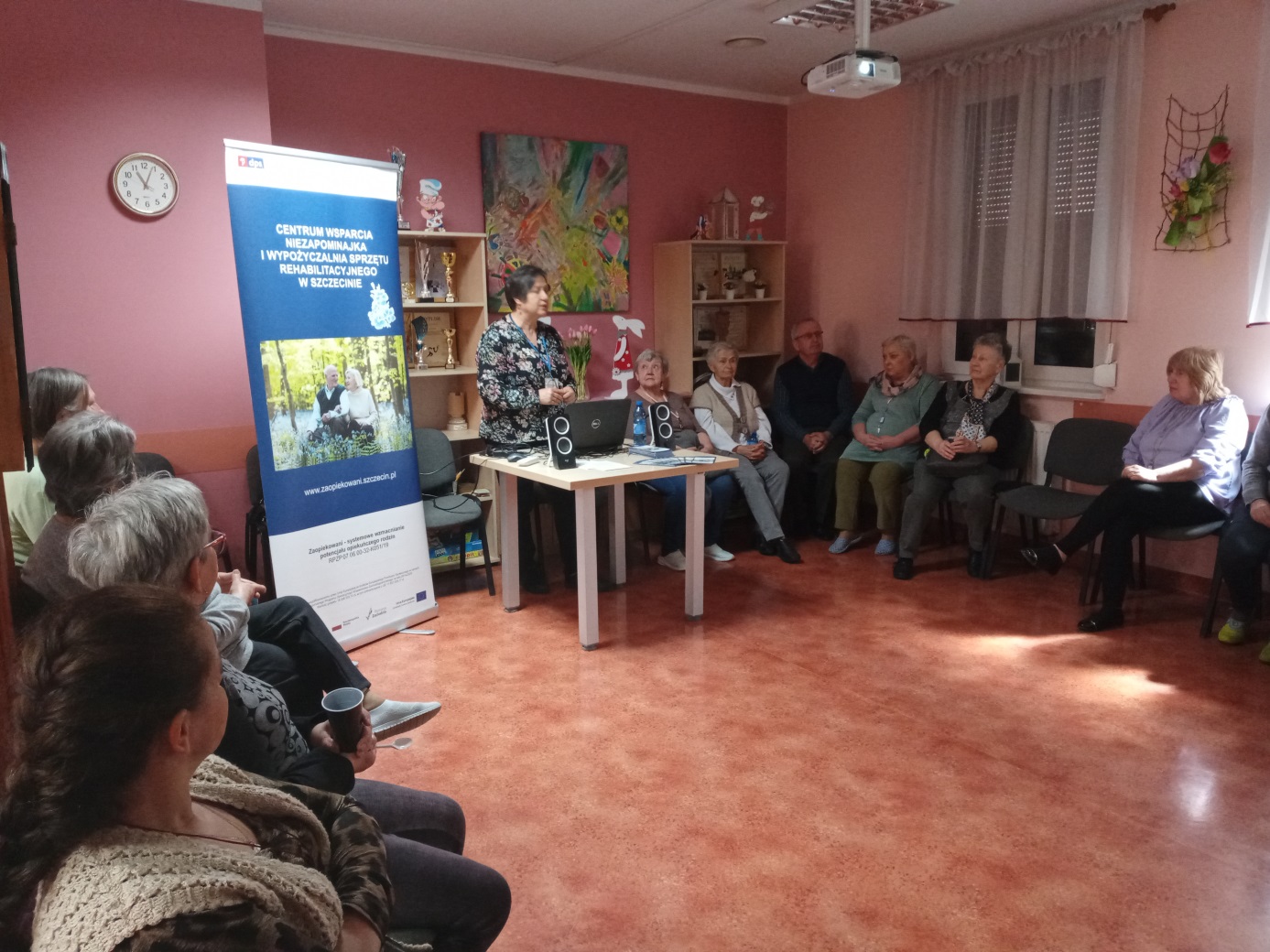 Kobieta wygłasza odczyt dla siedzących do okoła.