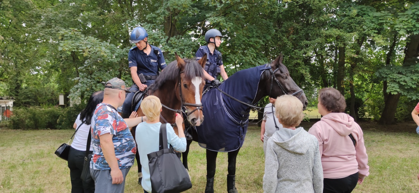Patrol policji konnej z ludźmi głąszczącymi konie.