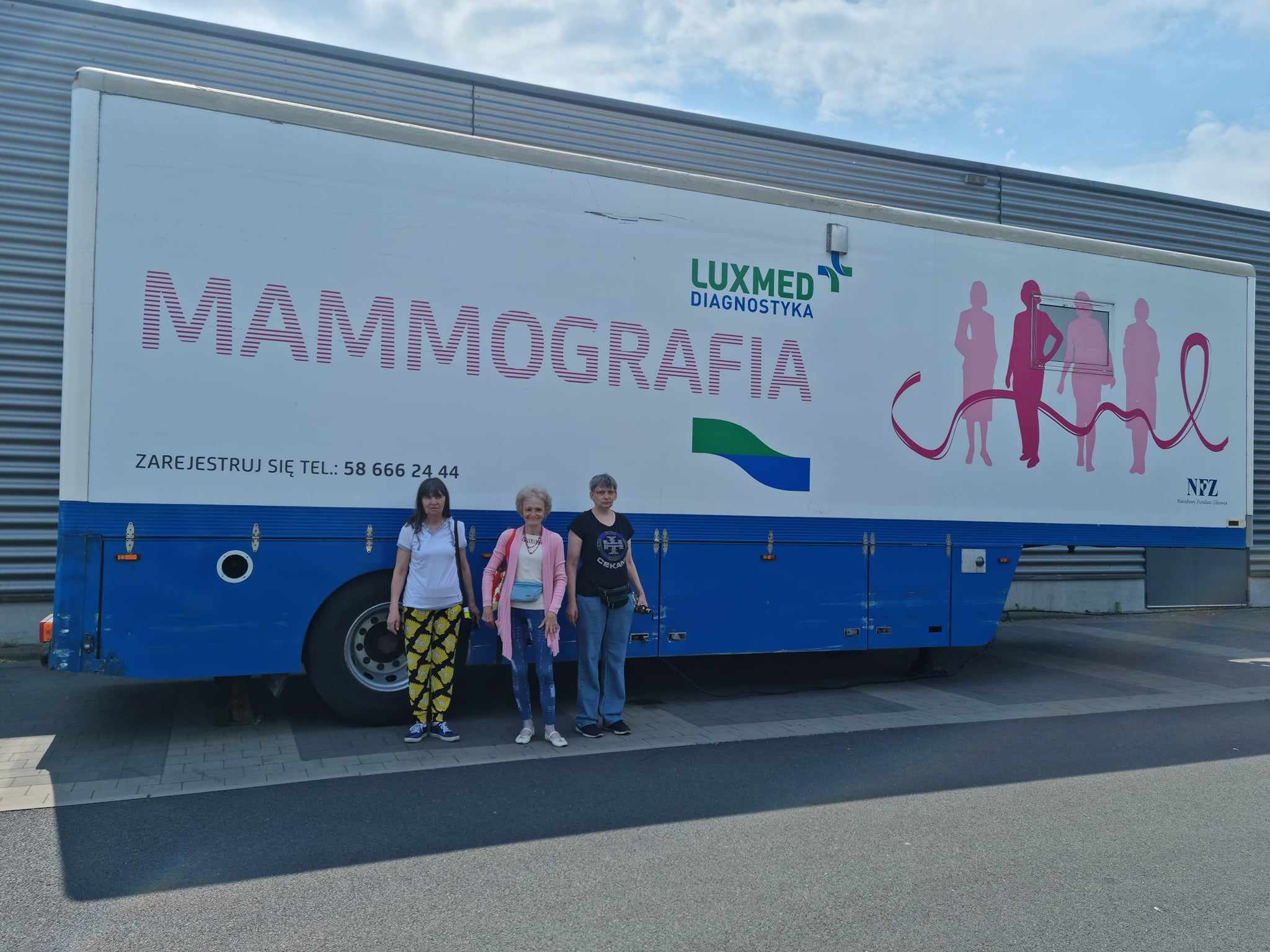 Kobiety stoją przed przyczepą mamobusu.