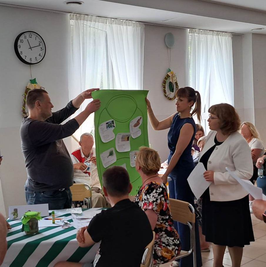 Ludzie przy stole trzymają płachtę z napisami.