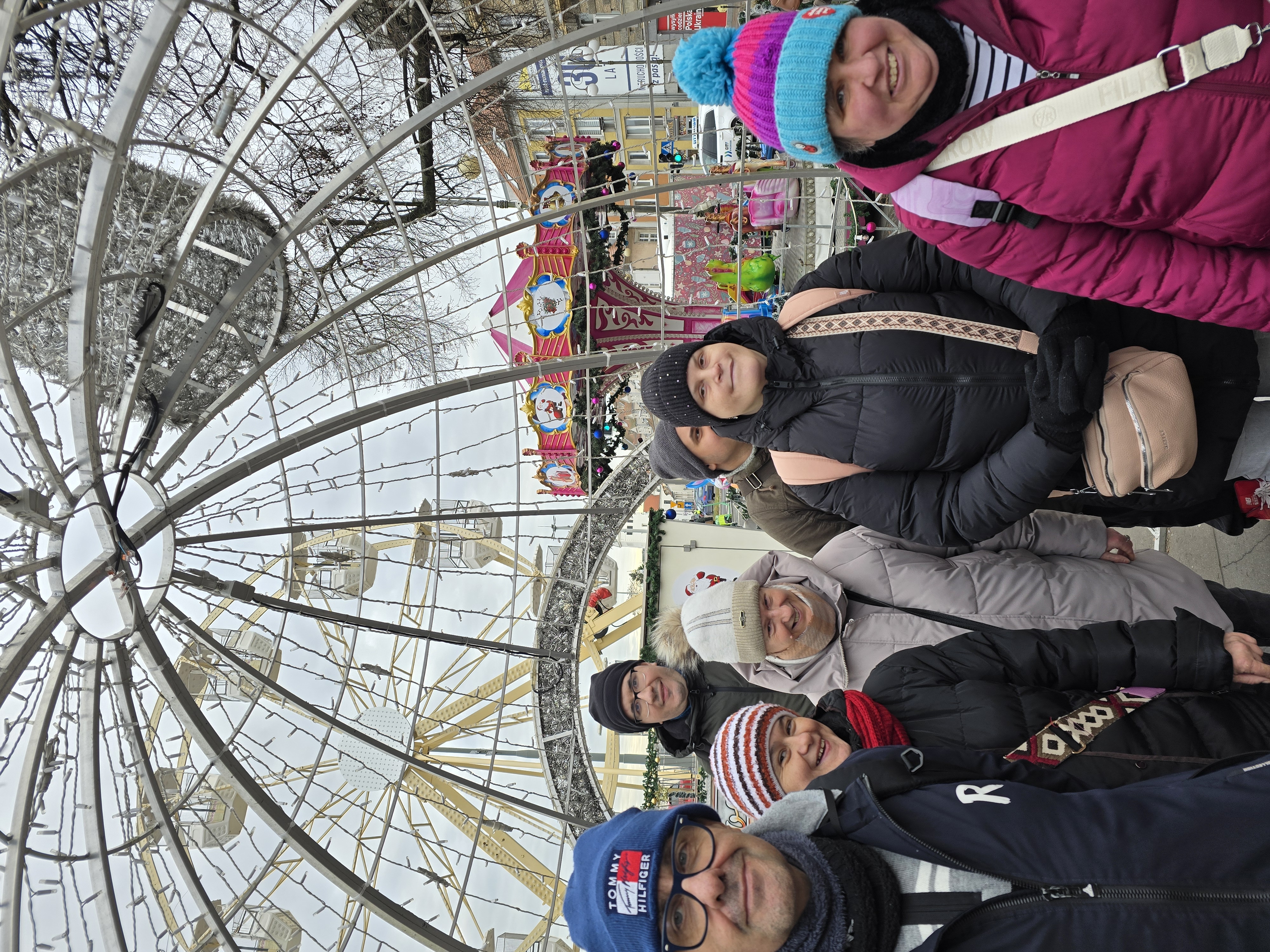 Grupa osób w ozdobie świątecznej na jarmarju świątecznym